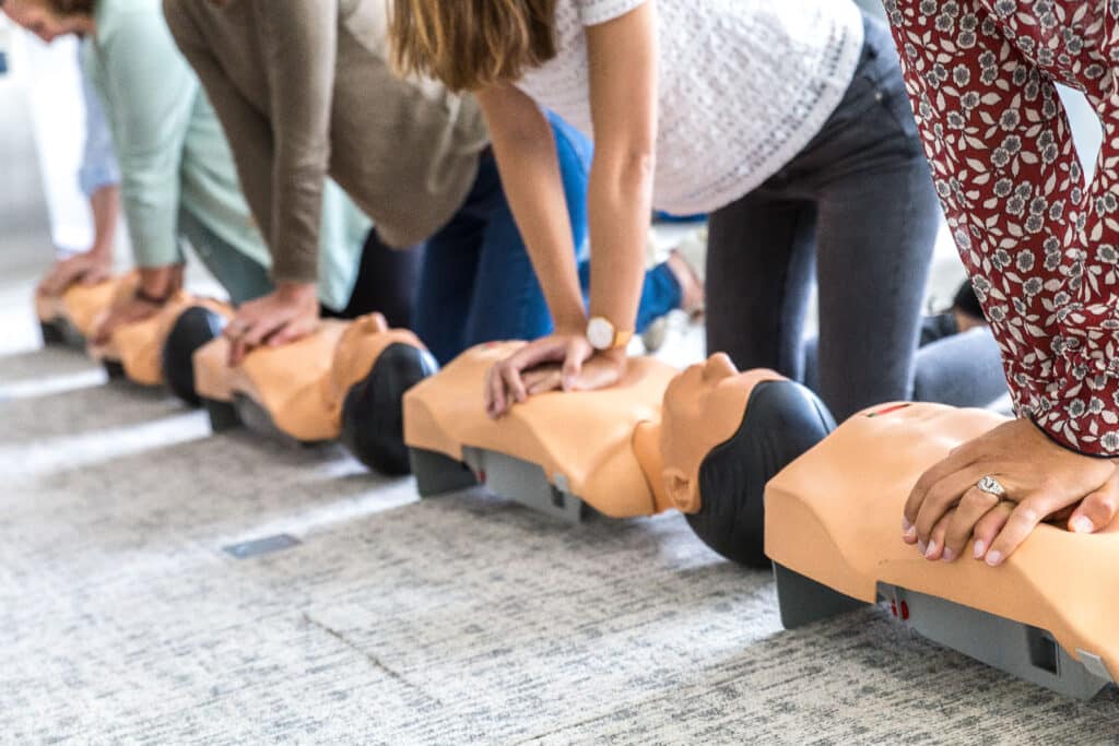 Hommes et femmes qui réalisent un massage cardiaque lors d'un team building